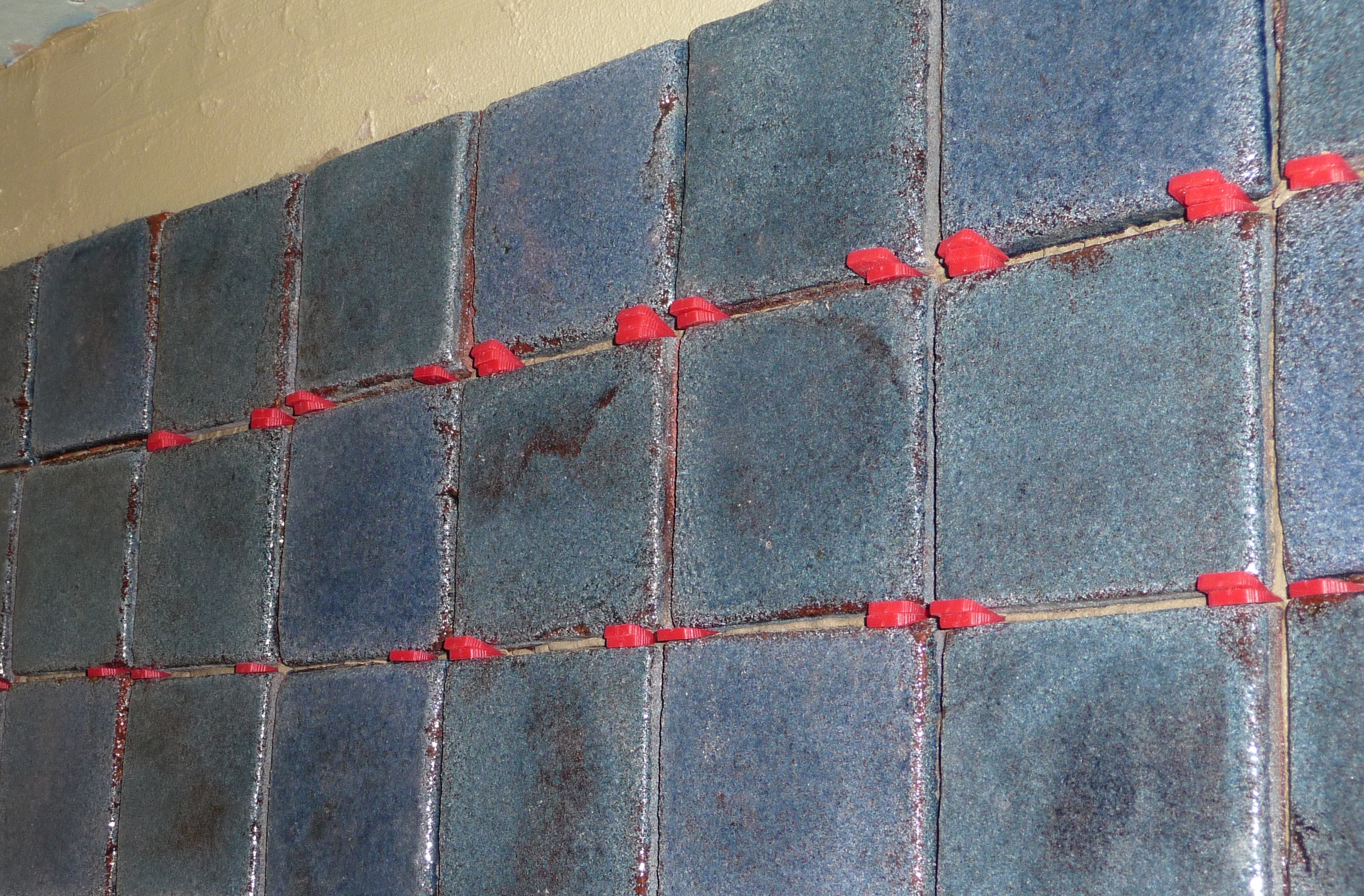 Spacers used in combination to give tile with purposeful size variation a consistent overall appearance.