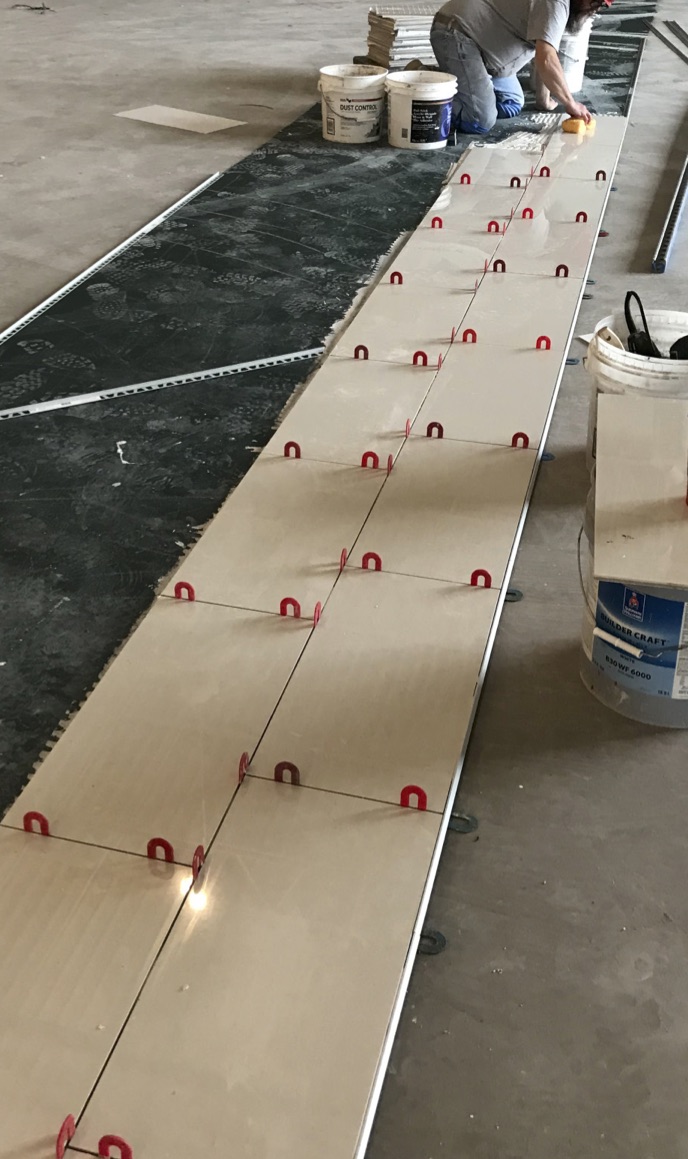 Tiling the main aisles of a furniture showroom requires precise layout to ensure tile rows are aligned on center with columns.