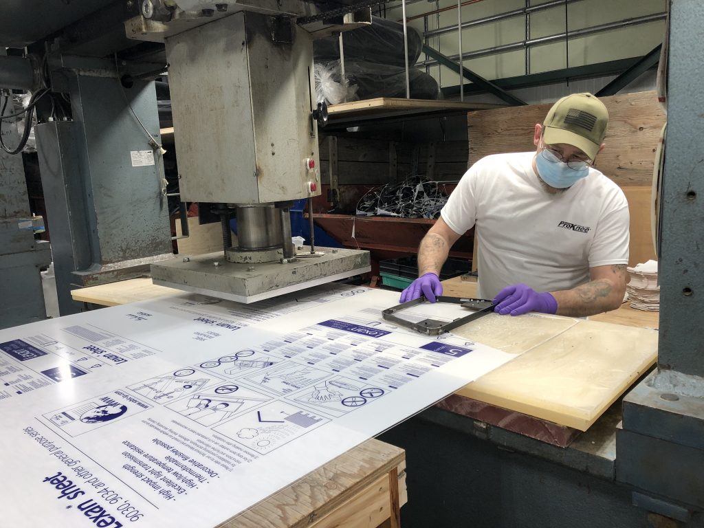 ProKnee employee with large Lexan Polycarbonate sheet for face shields

